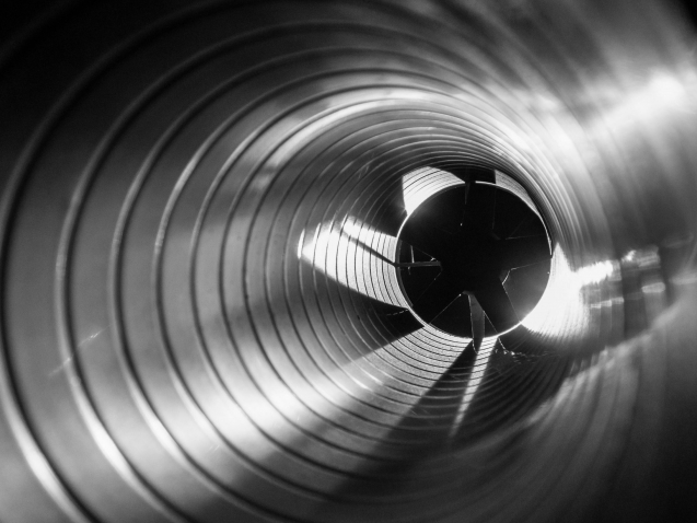 closeup view from inside the galvanized steel air duct on the exhaust fan in the background light, the front and back background is blurred with a bokeh effect